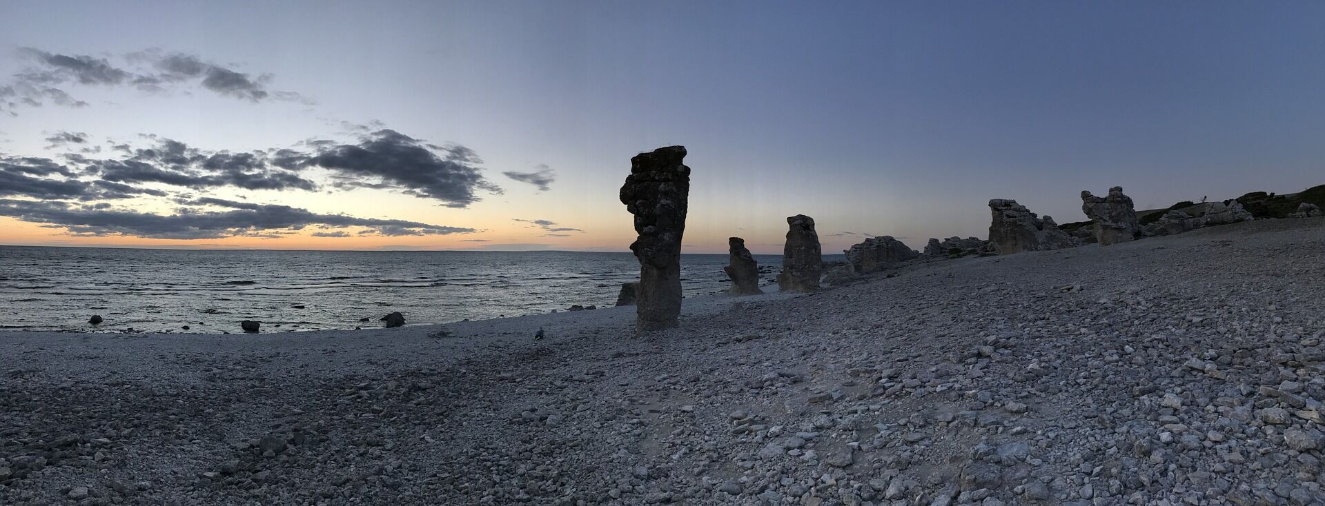 <span style="font-weight: 400;">A panoramic view of a rocky shoreline with distinctive sea stack formations under a sunset sky on Gotland, Sweden</span>