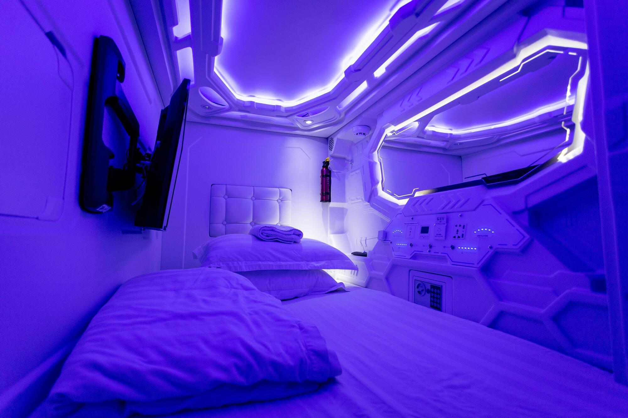 Capsule hotel room with futuristic blue lighting