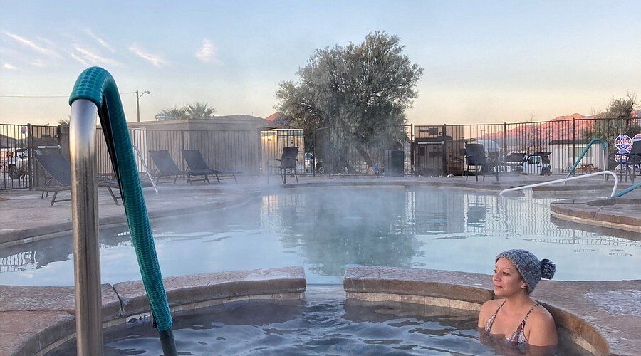 Woman relaxing in a steaming hot spring pool at Tecopa Hot Springs with a desert backdrop