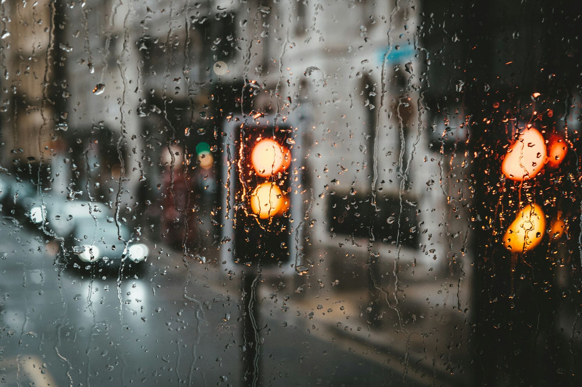 Raindrops on a window with blurred traffic lights in London