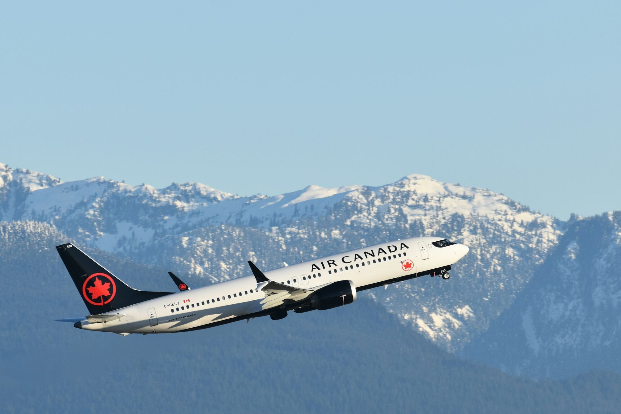 Air Canada plane taking off with snowy mountains in the background