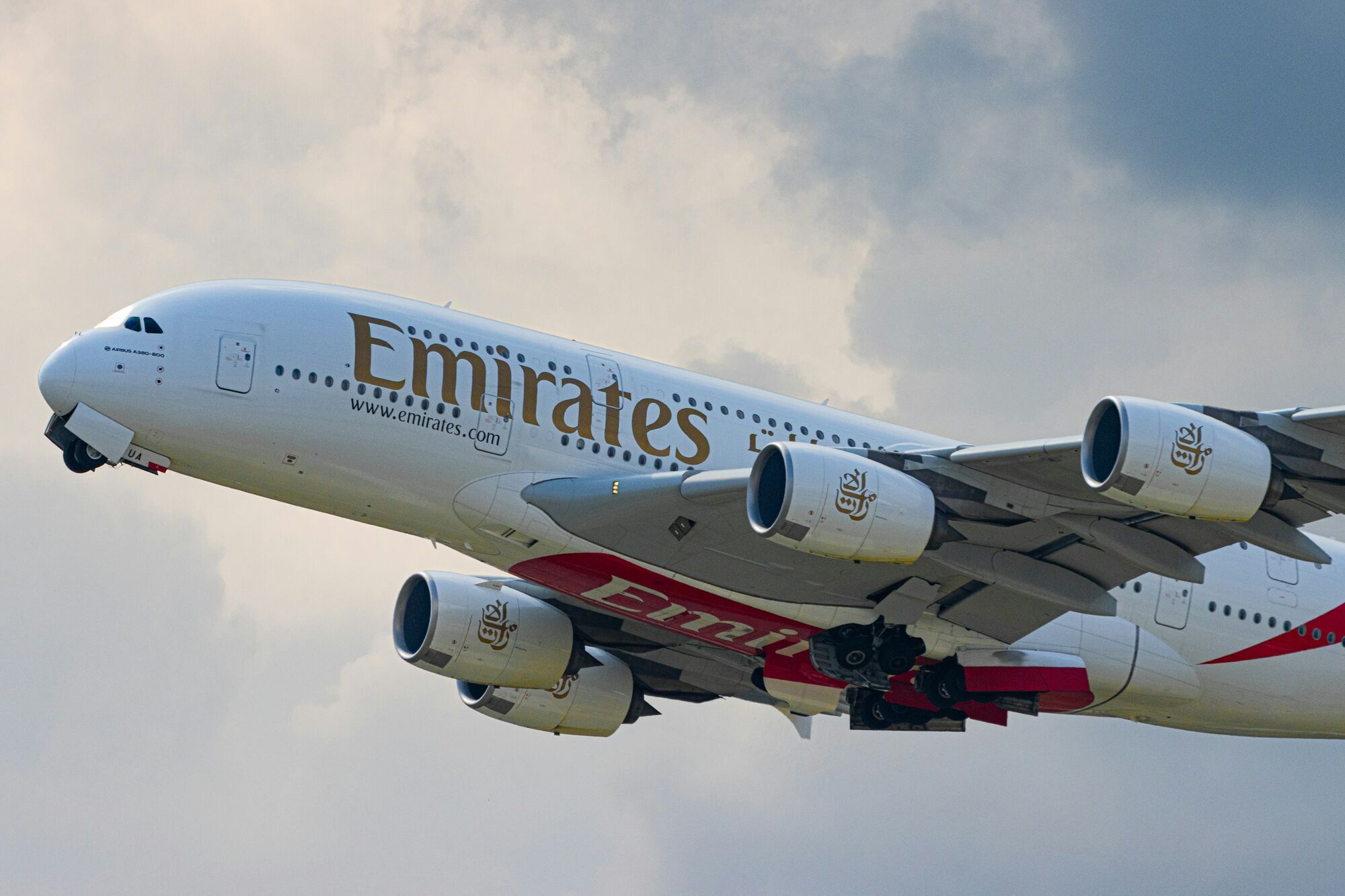 An Emirates Airbus A380 in flight against a cloudy sky