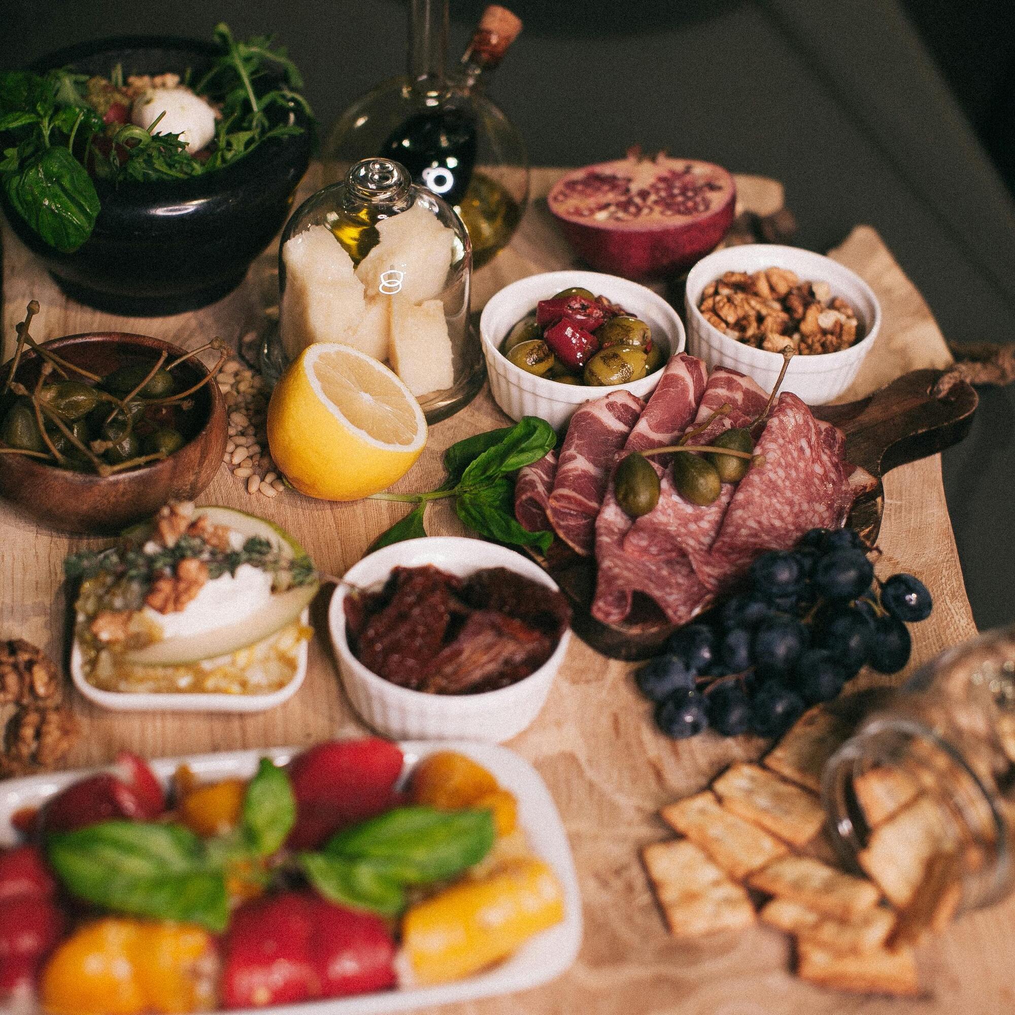 Assorted traditional holiday foods including cured meats, cheese, nuts, and fruits