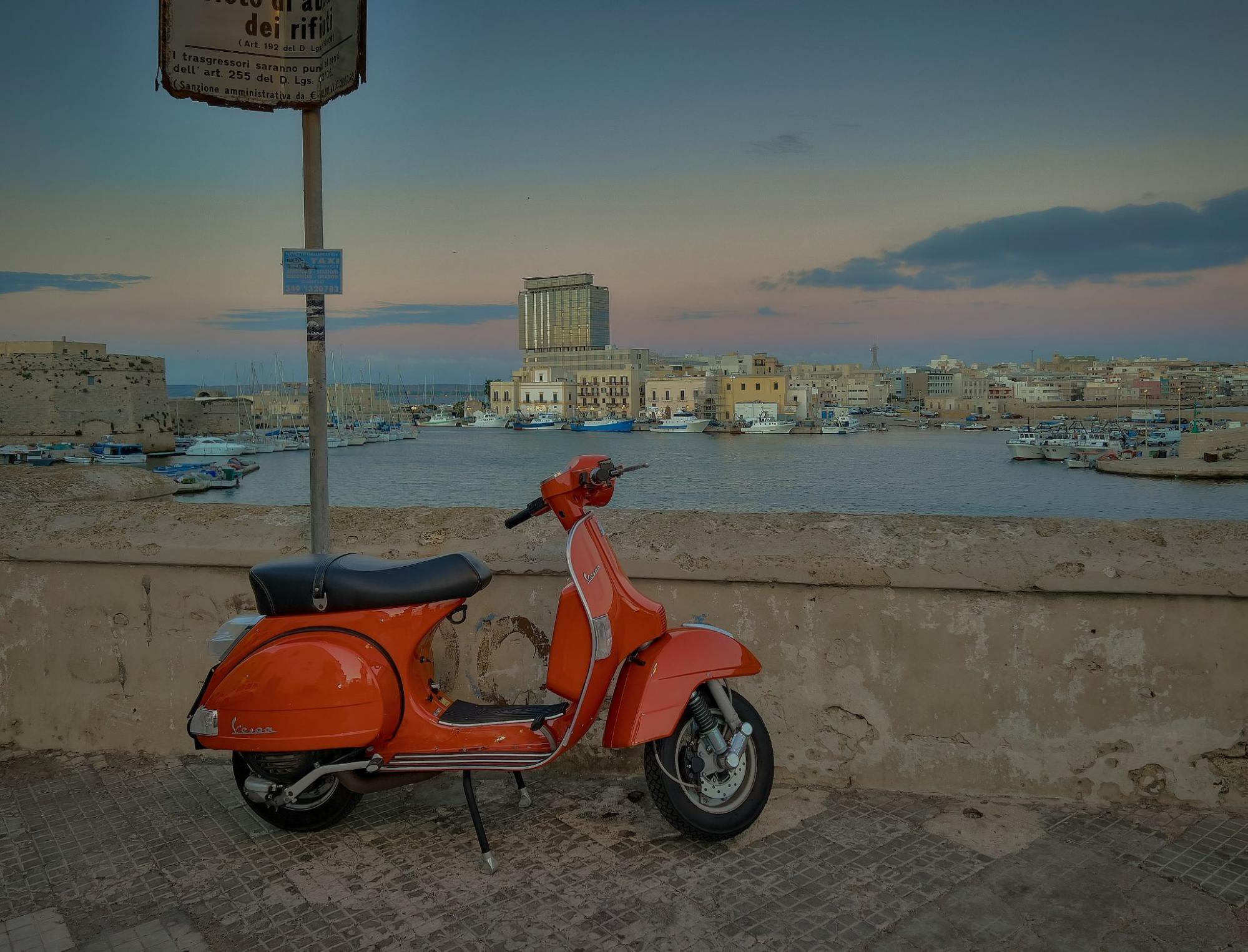 A red scooter parked in Lecce, Italy