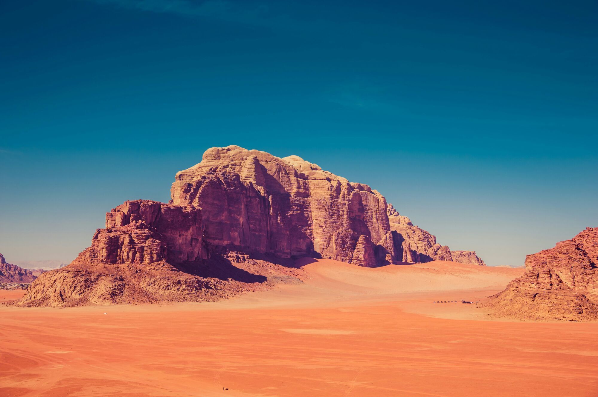 brown rock formation surrounded by sand dunes