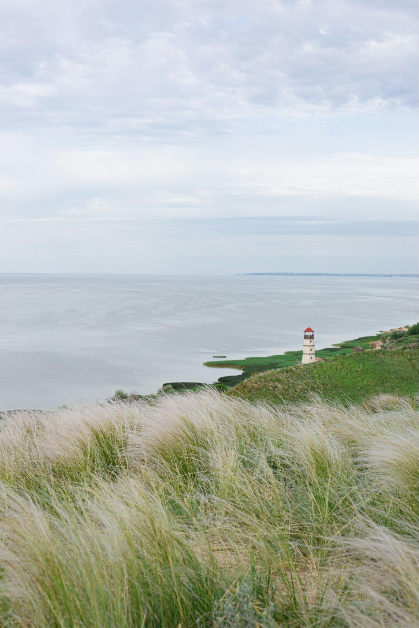 Coastal view of grassy dunes and a lighthouse