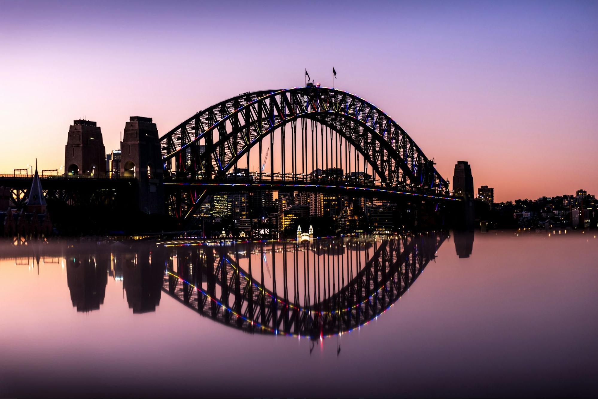 Sydney Harbour Bridge reflecting on still water at sunset