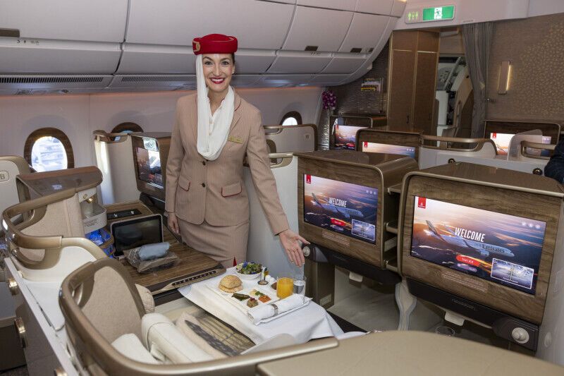 Emirates flight attendant presents meal service in the A350 Premium Economy cabin