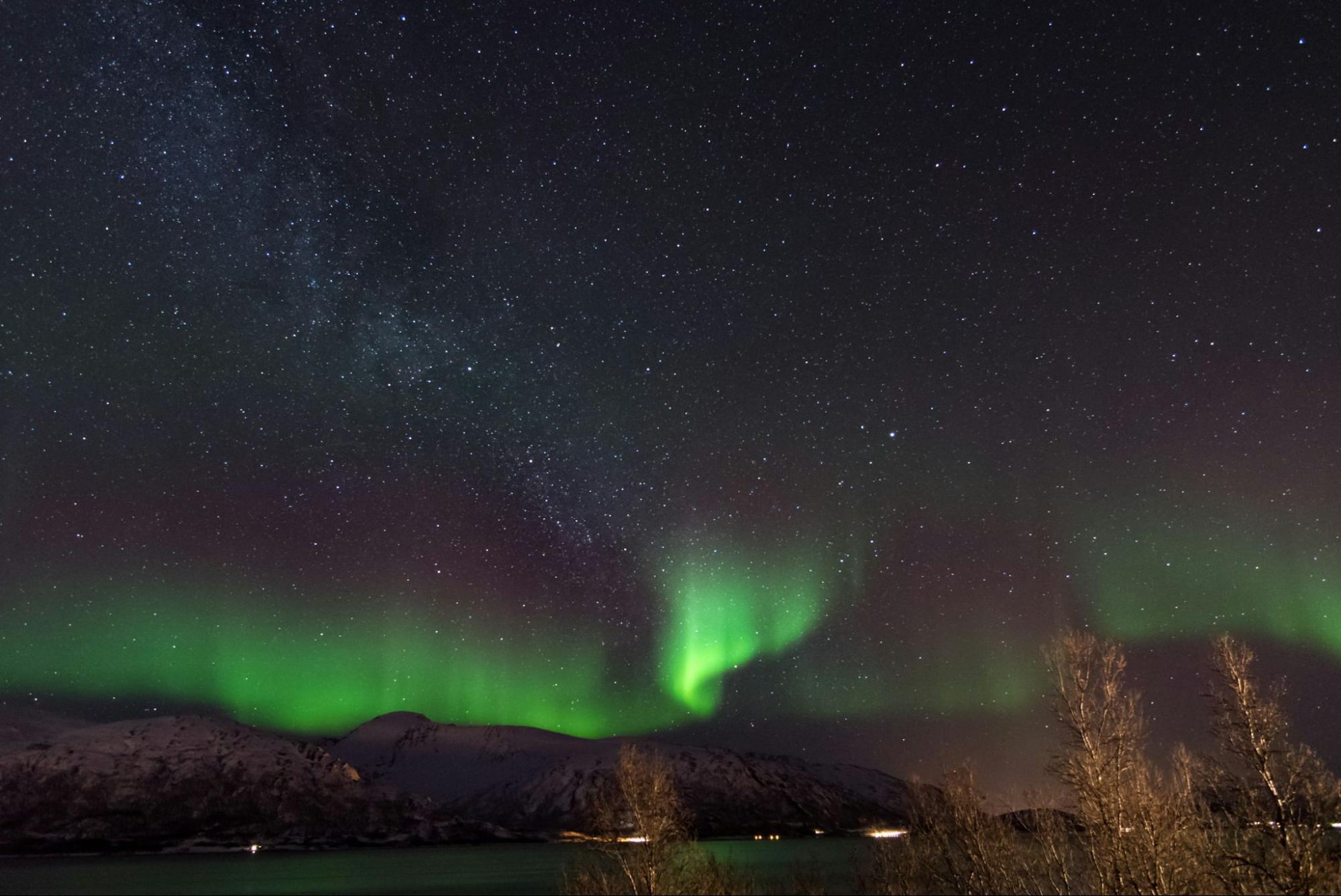 Northern Lights shining over snowy Norwegian mountains at night
