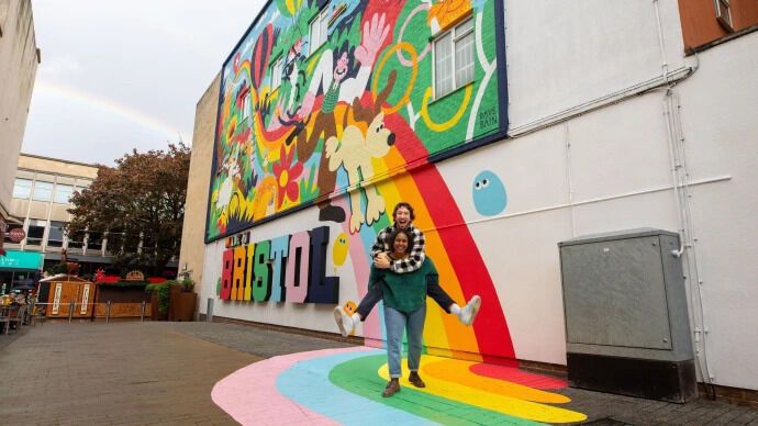 Couple posing by a colourful mural in Bristol city centre