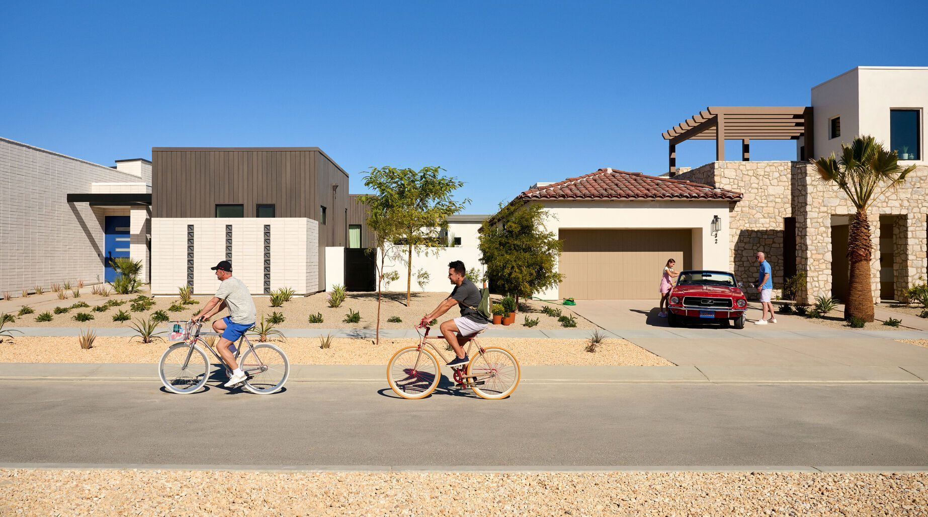 Residents biking through Cotino community streets with modern desert-style homes in the background