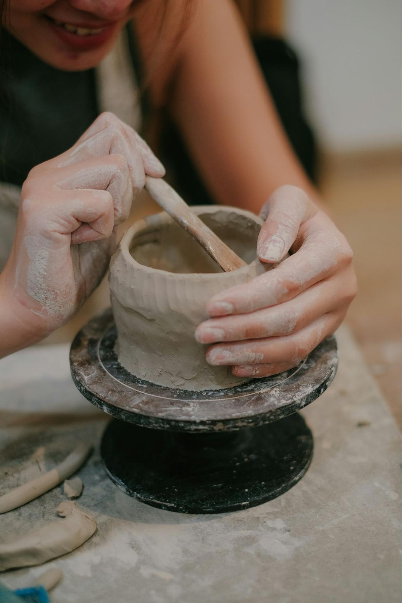 Hands shaping a clay pot on a pottery wheel during an artisan workshop