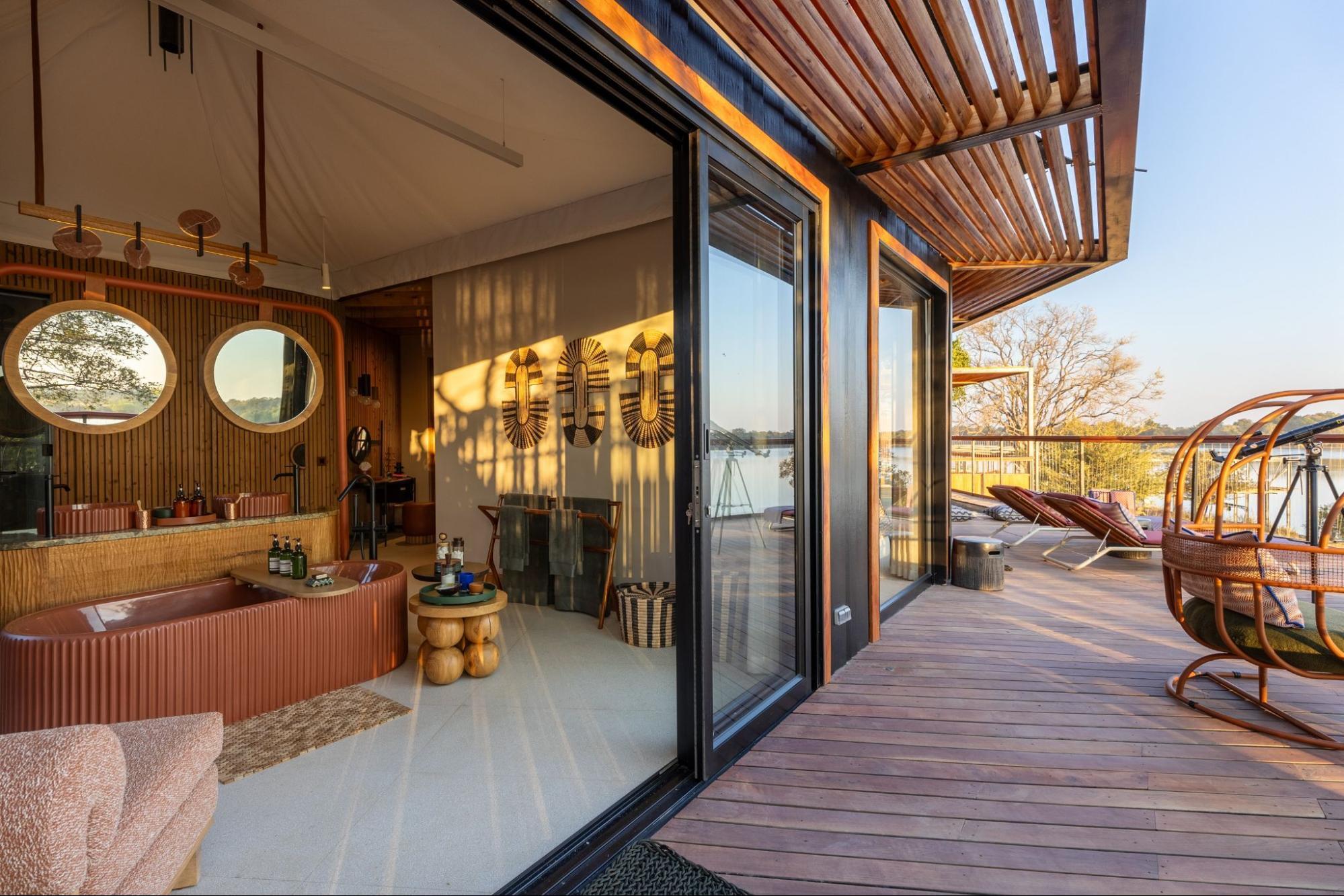 Interior and terrace view of a tented villa at Anantara Kafue River Tented Camp in Zambia, overlooking the Kafue River at sunset