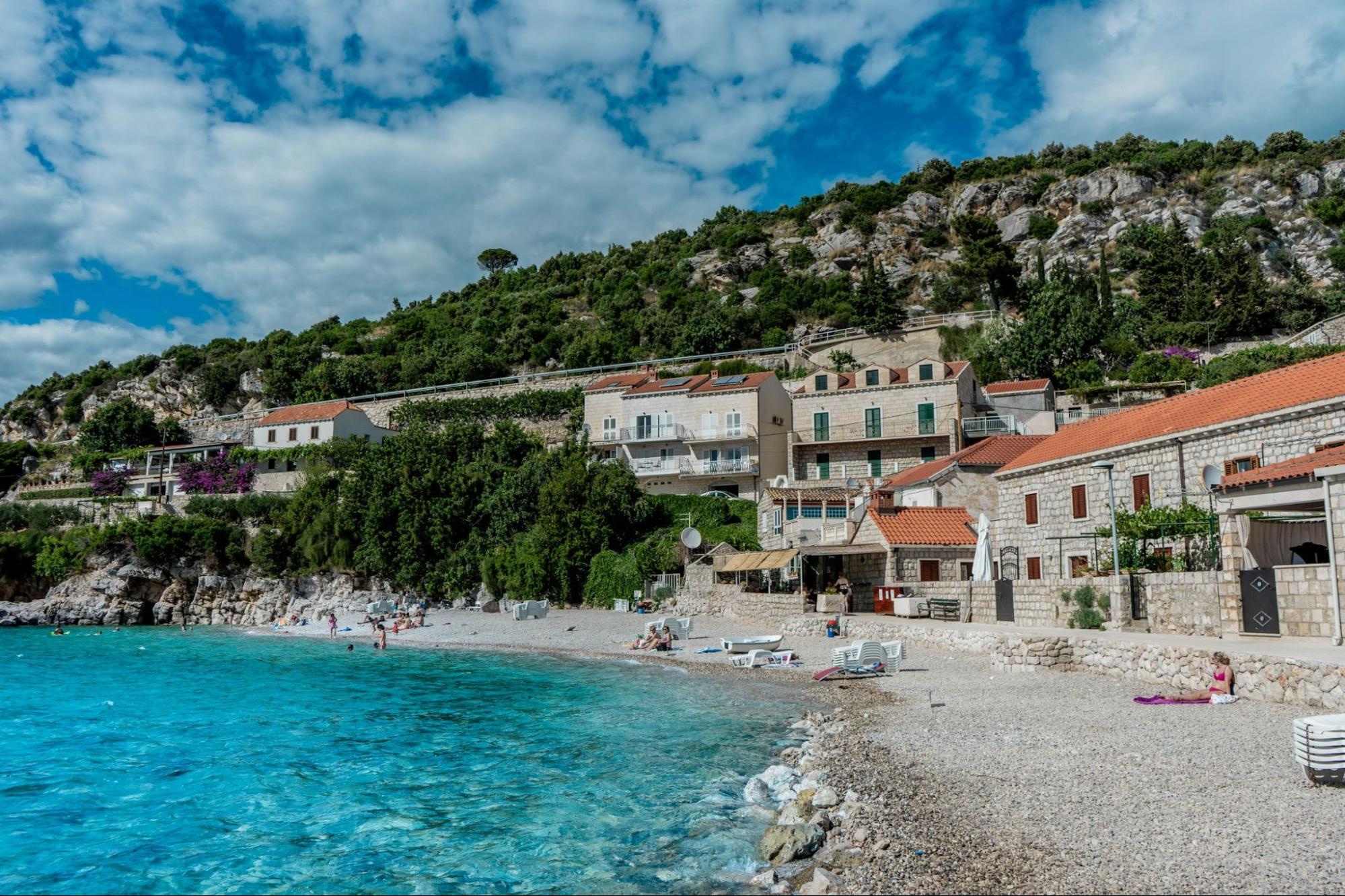 A quiet beach with turquoise water and stone houses along the Croatian coast