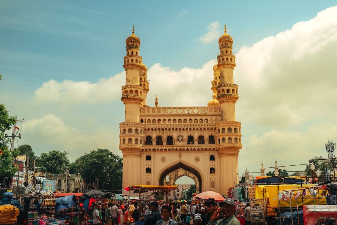 Charminar monument in Hyderabad surrounded by a busy market under a partly cloudy sky