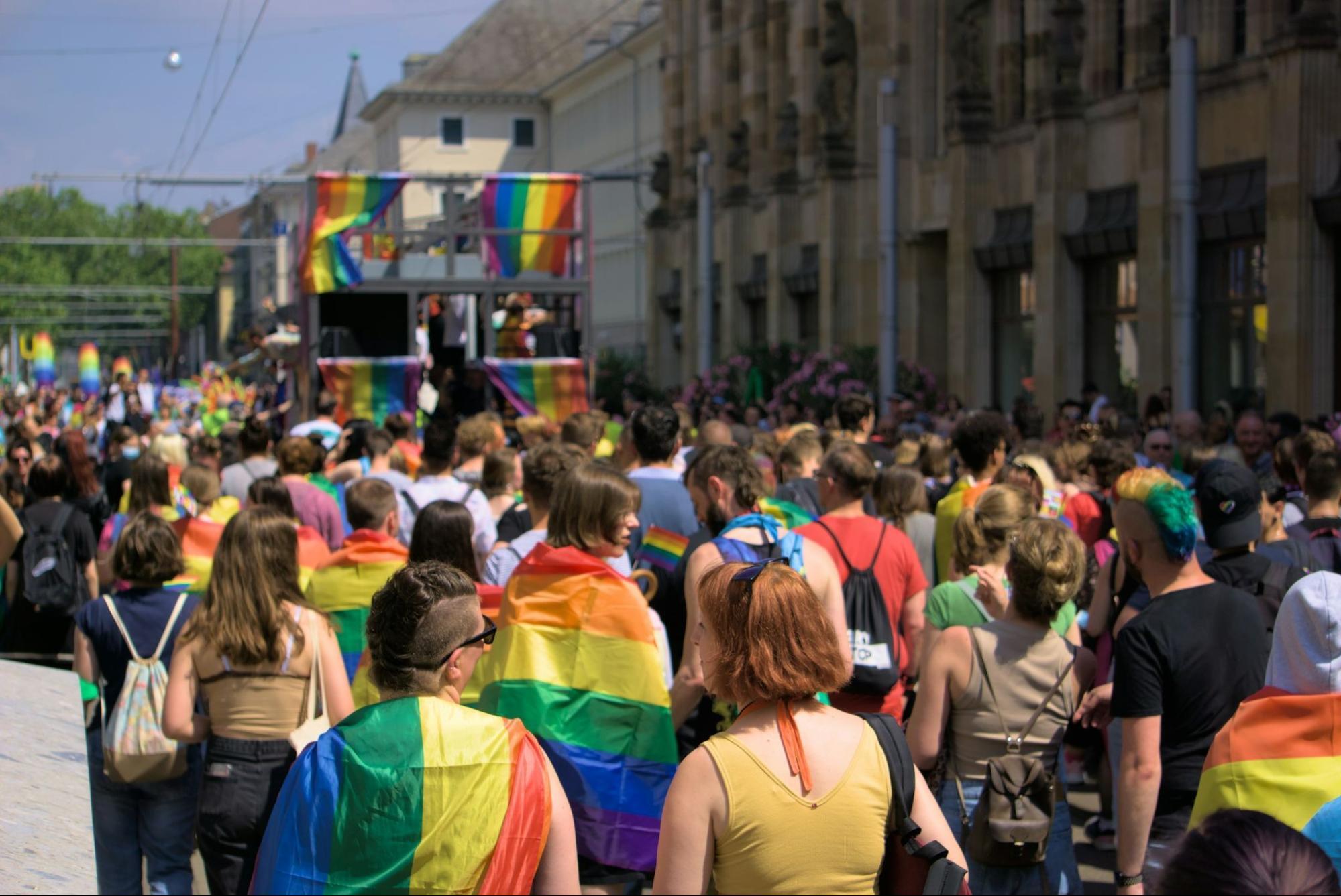 Participants at a Pride parade wrapped in rainbow flags