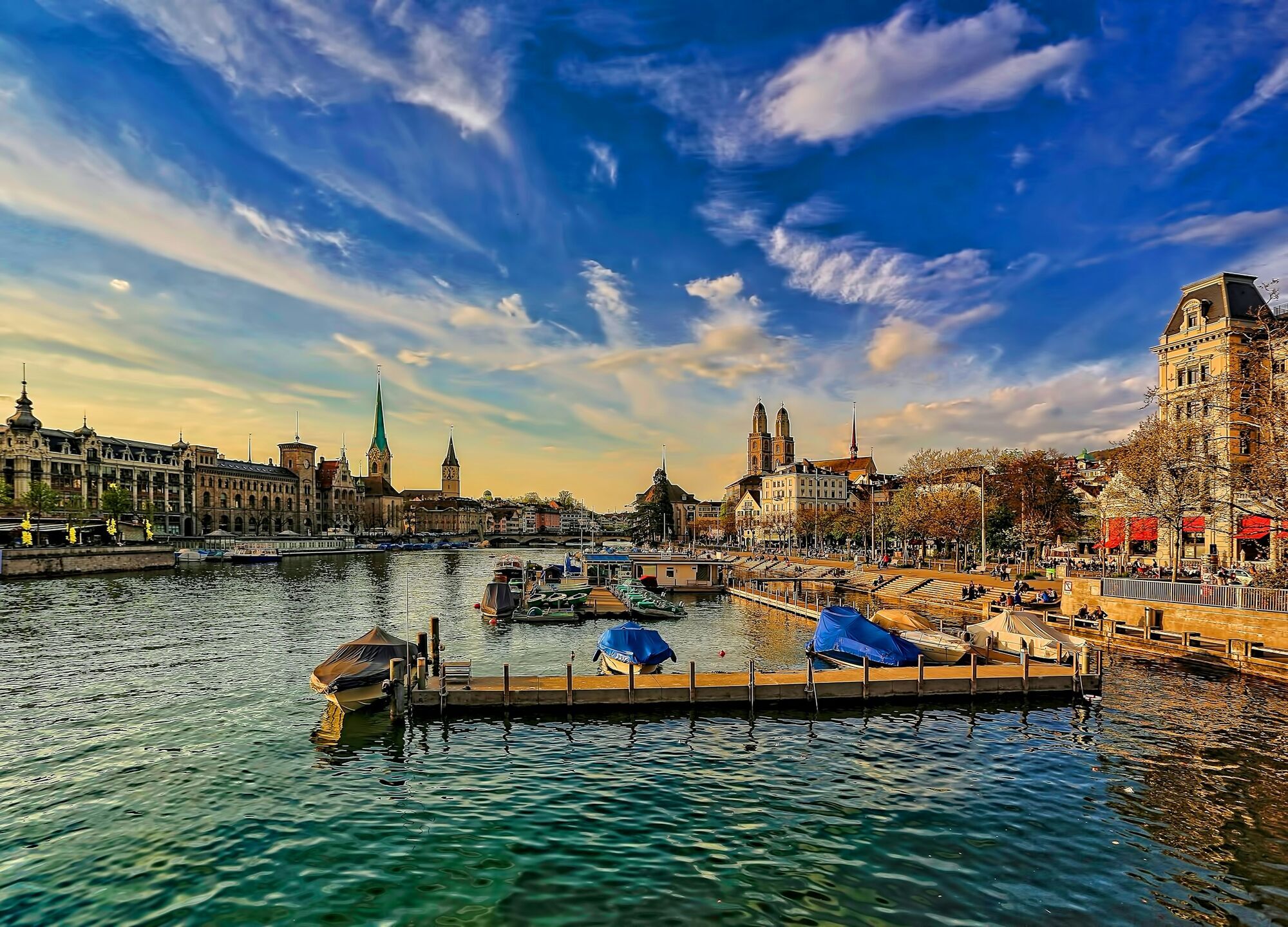 Boats moored along the Limmat River with Zürich’s skyline at sunset