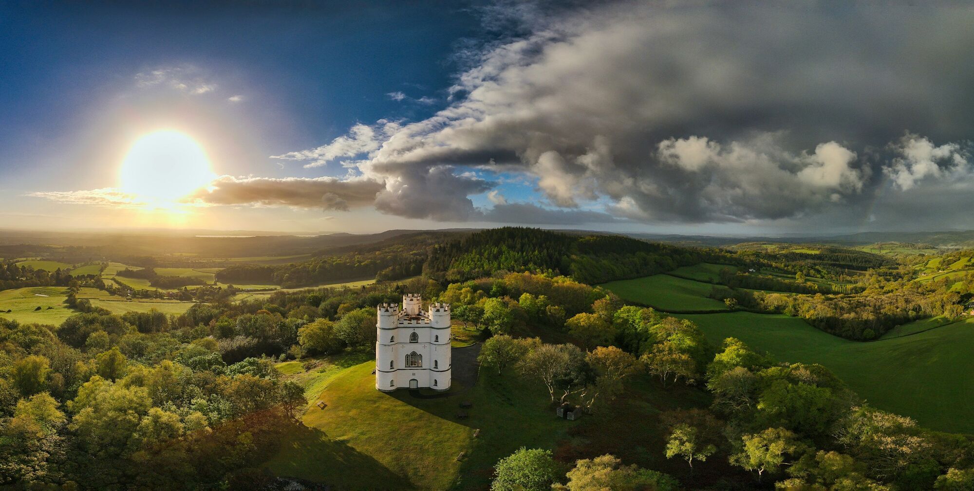 Sunset view over Exeter countryside with a historic castle surrounded by rolling green hills