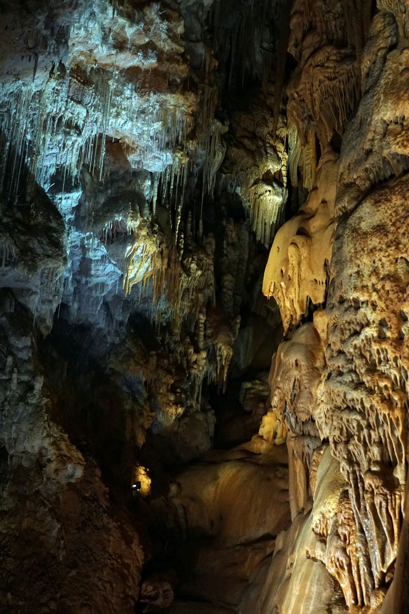 Illuminated cave interior with stalactites and textured rock formations