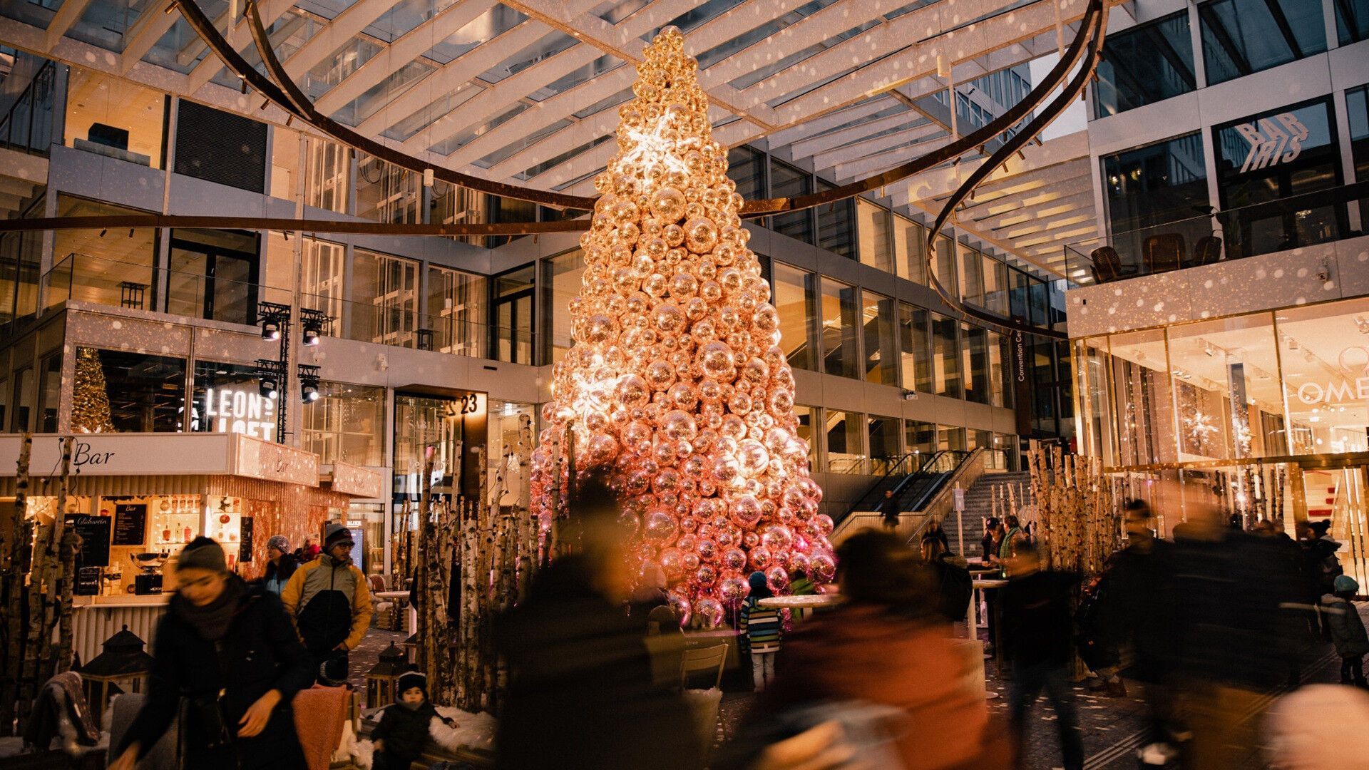 Visitors walking past a large illuminated Christmas tree at The Circle in Zurich Airport during Advent