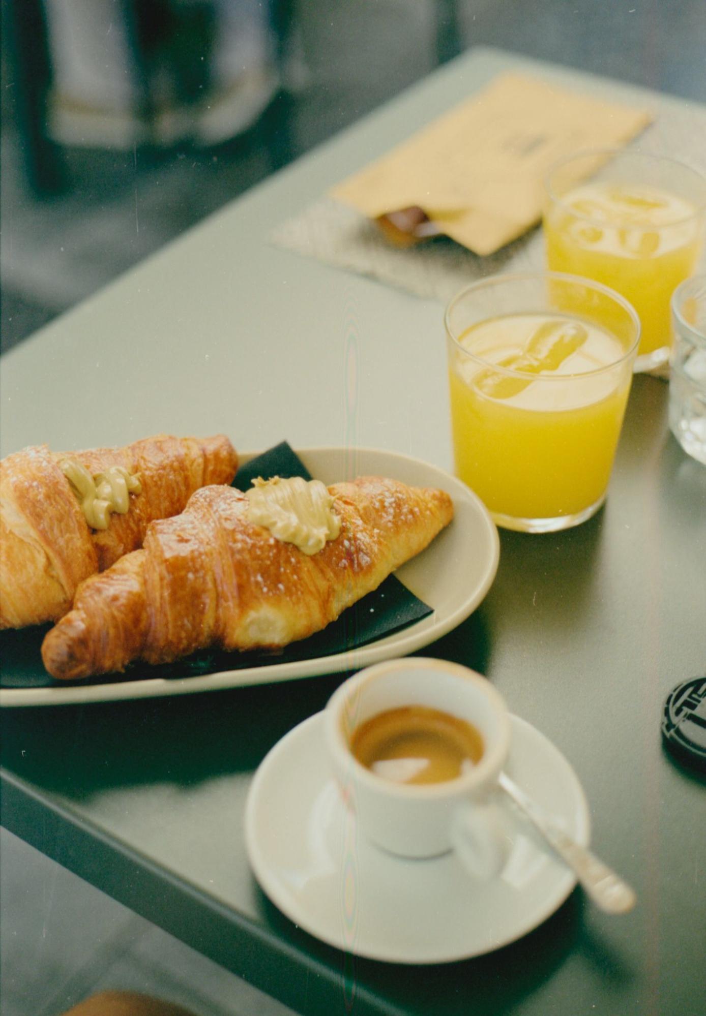 Breakfast setup with pastries, juice, and espresso on a hotel table