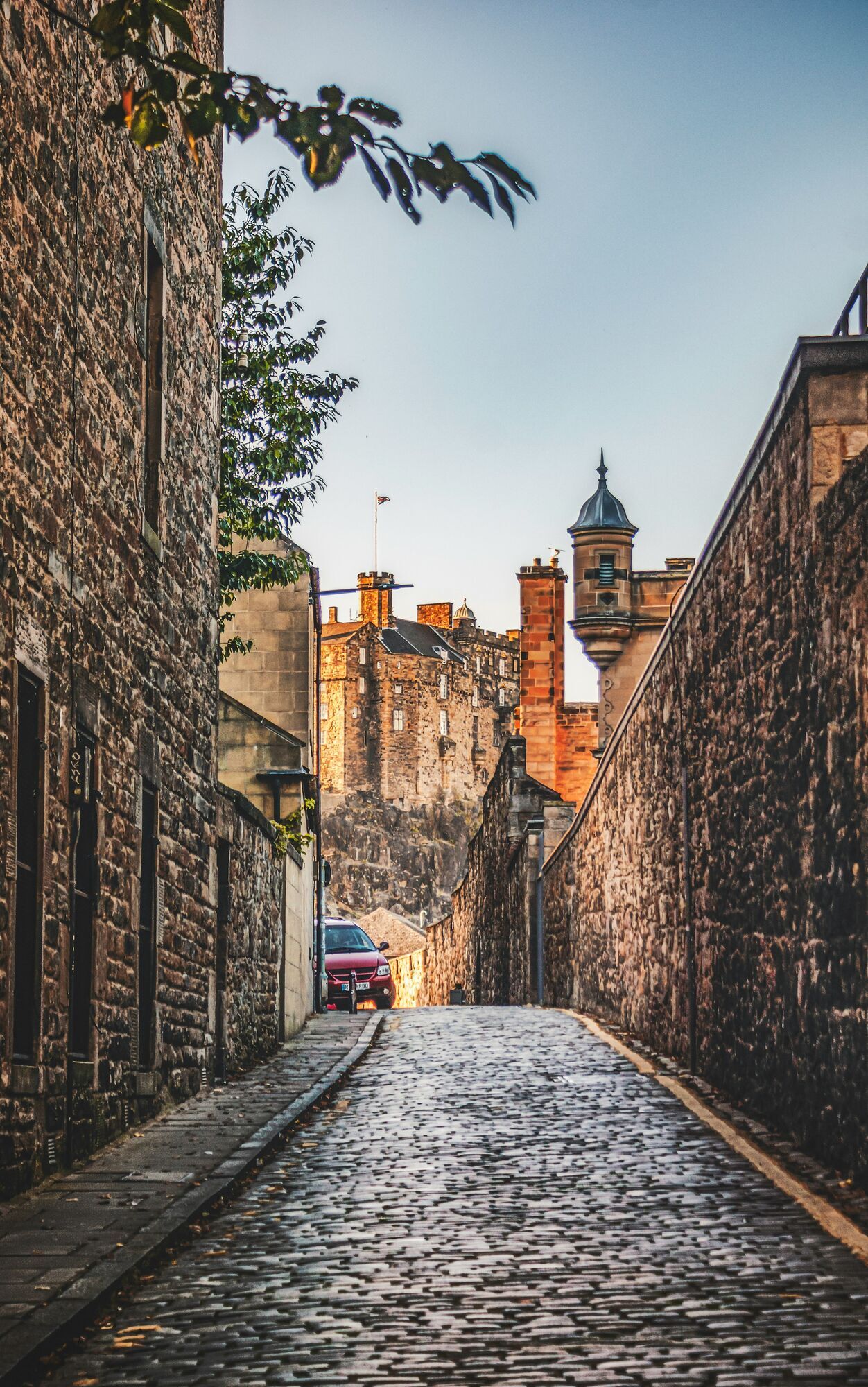 Narrow cobbled street leading toward an old Scottish castle