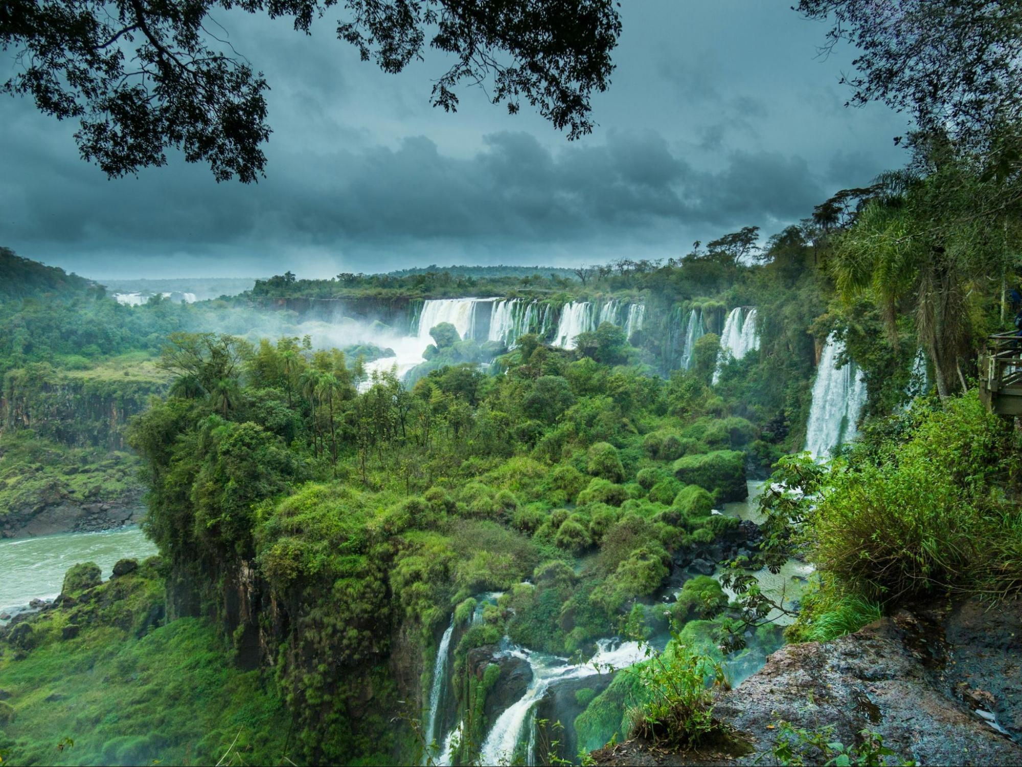 Panoramic view of Iguaçu Falls surrounded by lush green rainforest under cloudy skies