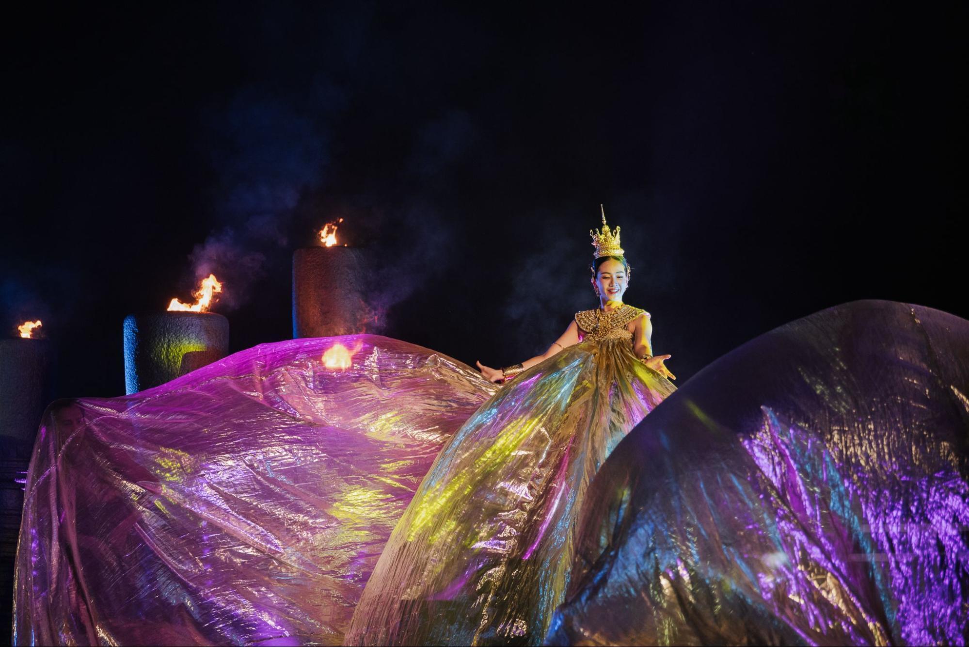 Thai performer in golden costume during a cultural stage show with fire effects