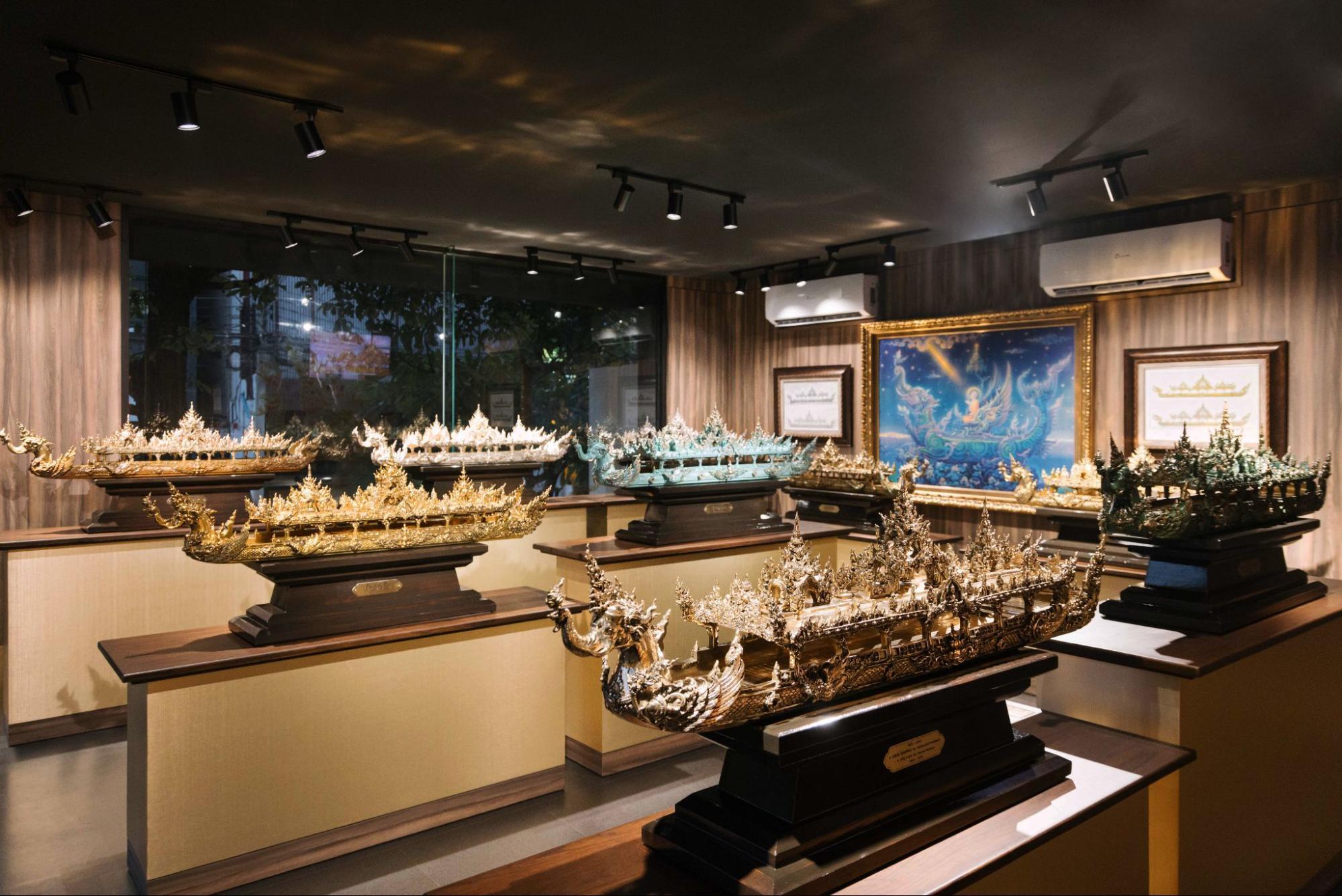 Intricately crafted scale models of traditional Thai vessels displayed inside a museum gallery
