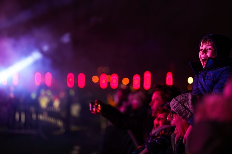 Excited child watching a colourful light show among a crowd at night