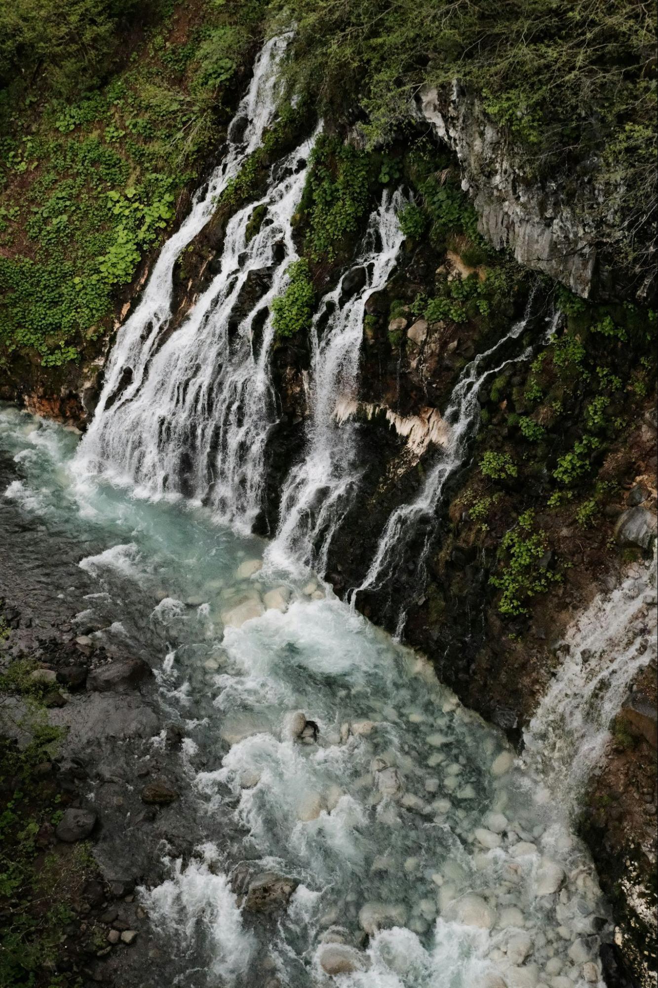 Waterfall flowing over rocky cliffs into a clear stream