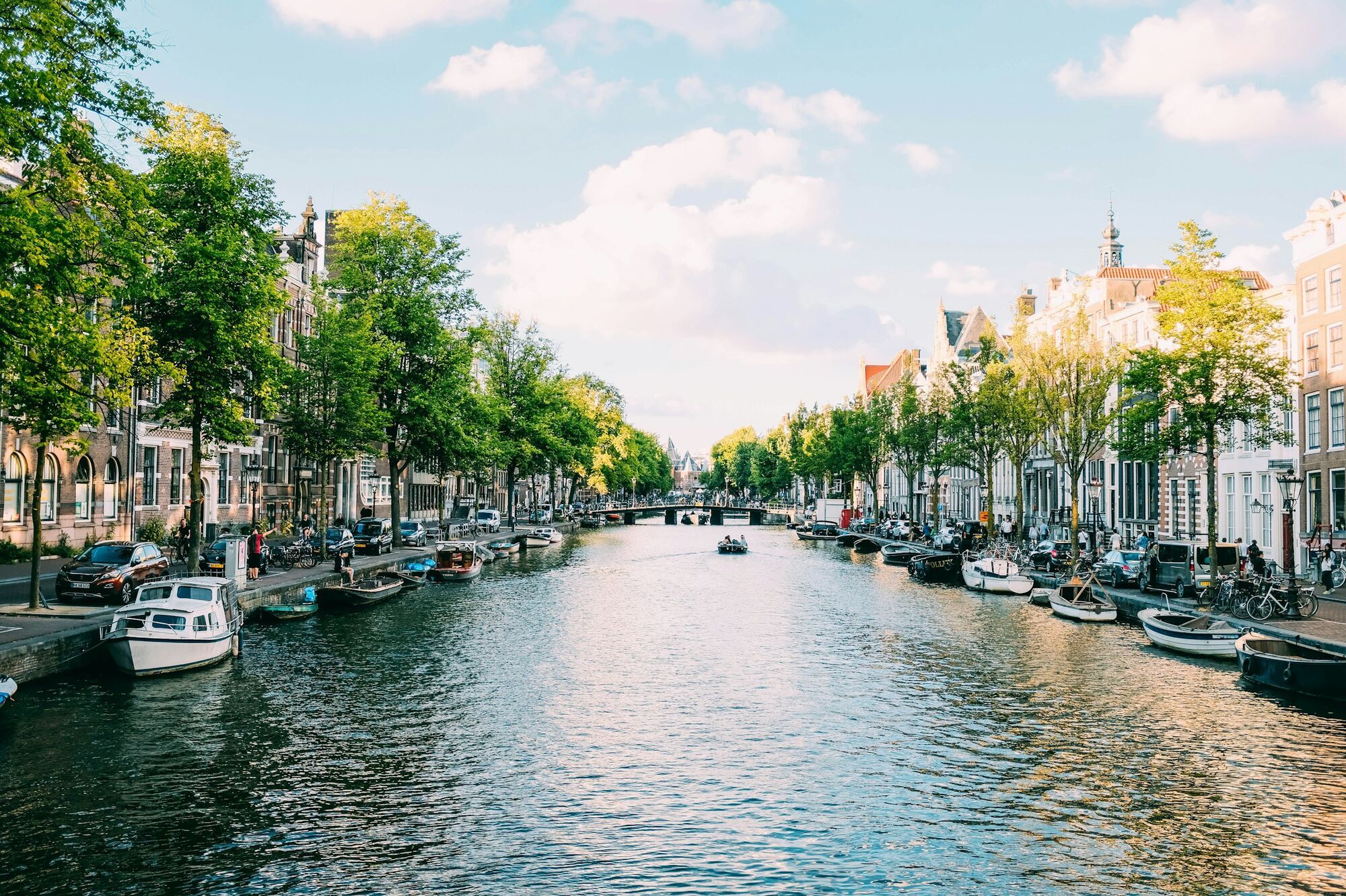 Scenic Amsterdam canal with boats and historic buildings under a clear sky