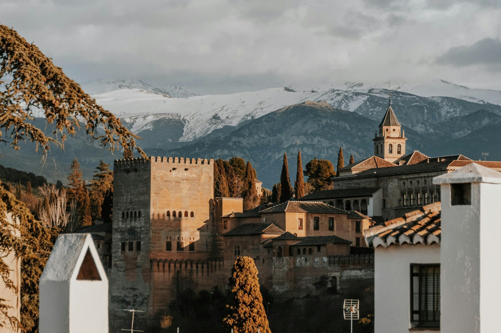 The Alhambra in Granada with the Sierra Nevada mountains in the background, bathed in warm sunlight