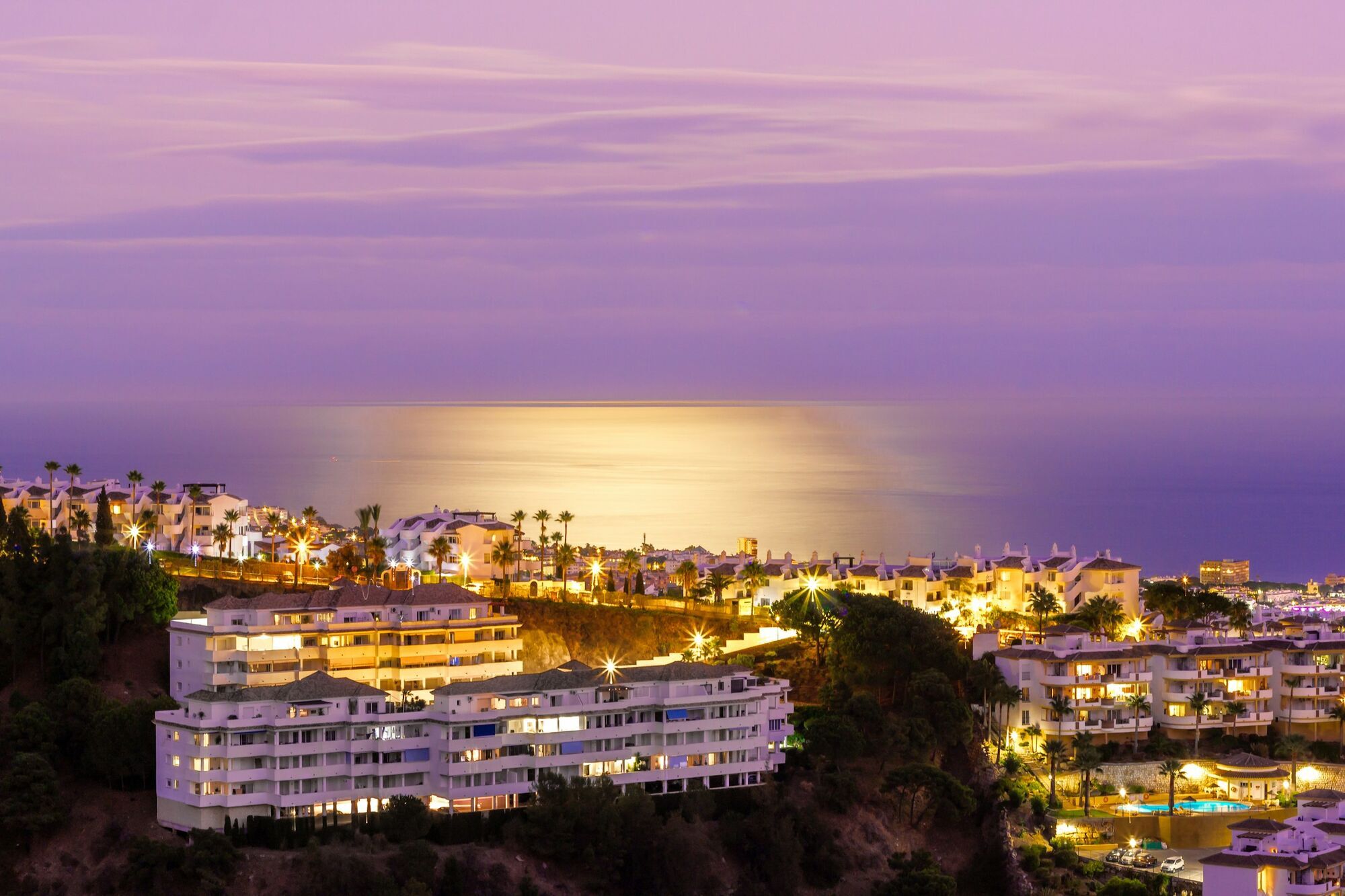 Scenic evening view of Marbella coastline with illuminated buildings and sea reflection