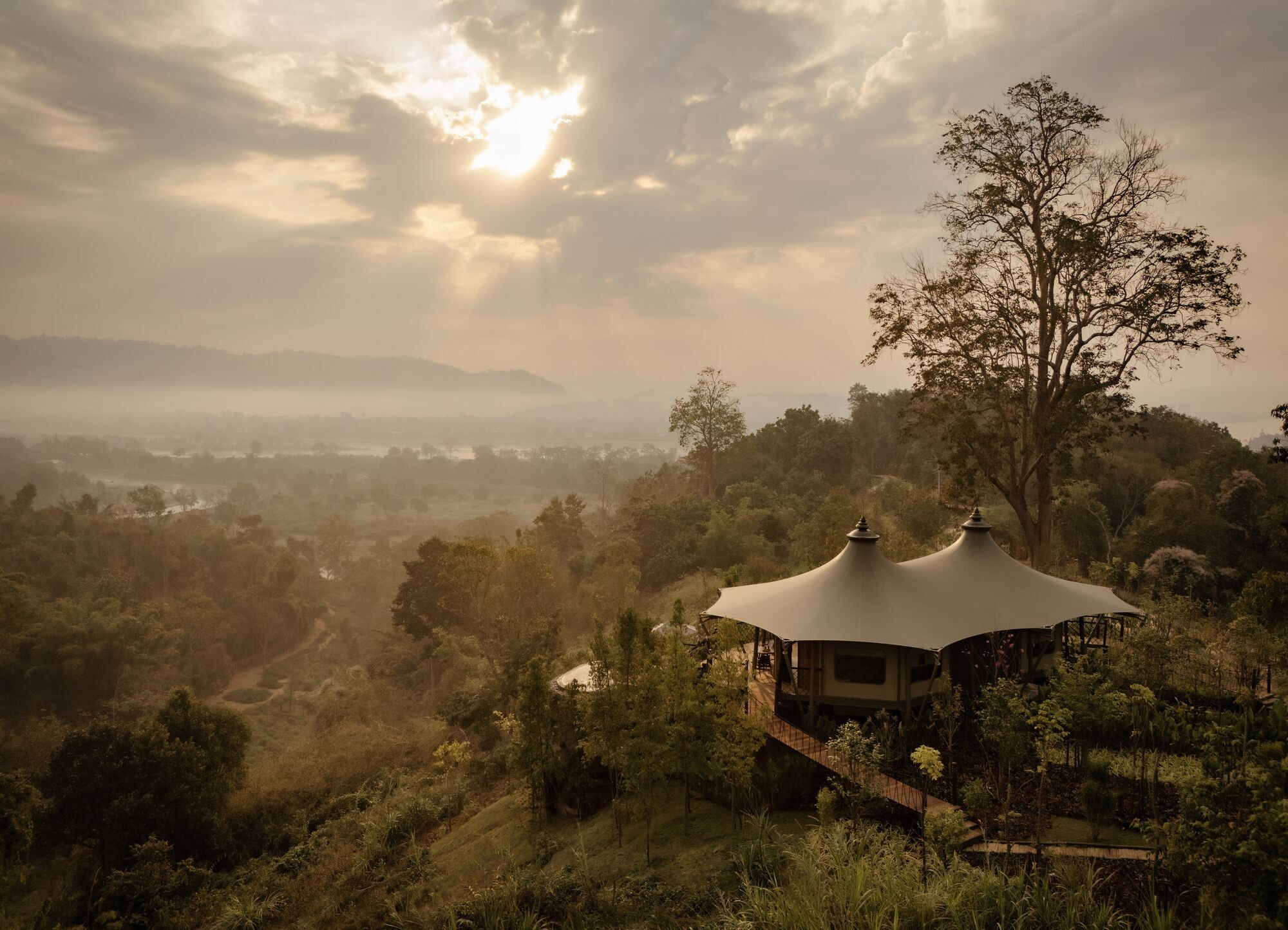 A luxury tented retreat overlooking misty jungle landscapes at sunrise in Northern Thailand