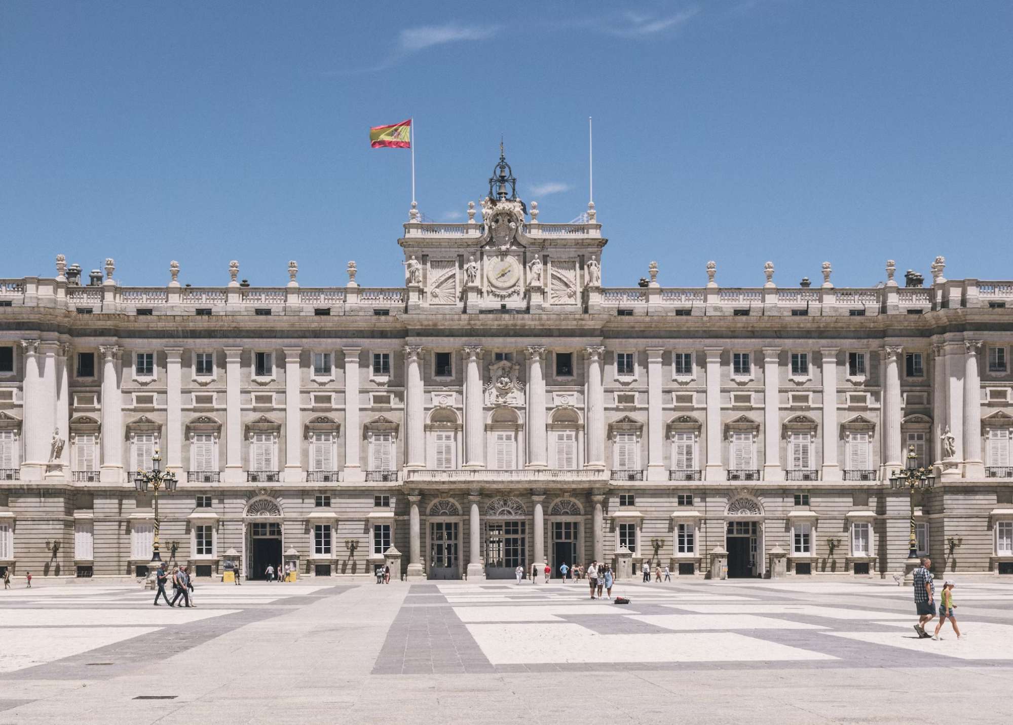 Royal Palace of Madrid under a clear sky with Spanish flag flying