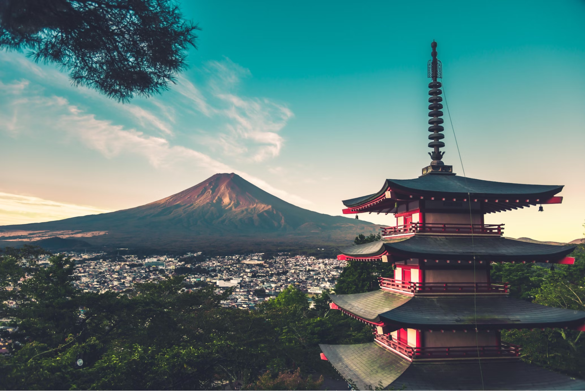 A breathtaking view of Mount Fuji towering over a nearby city, with clear skies and lush greenery