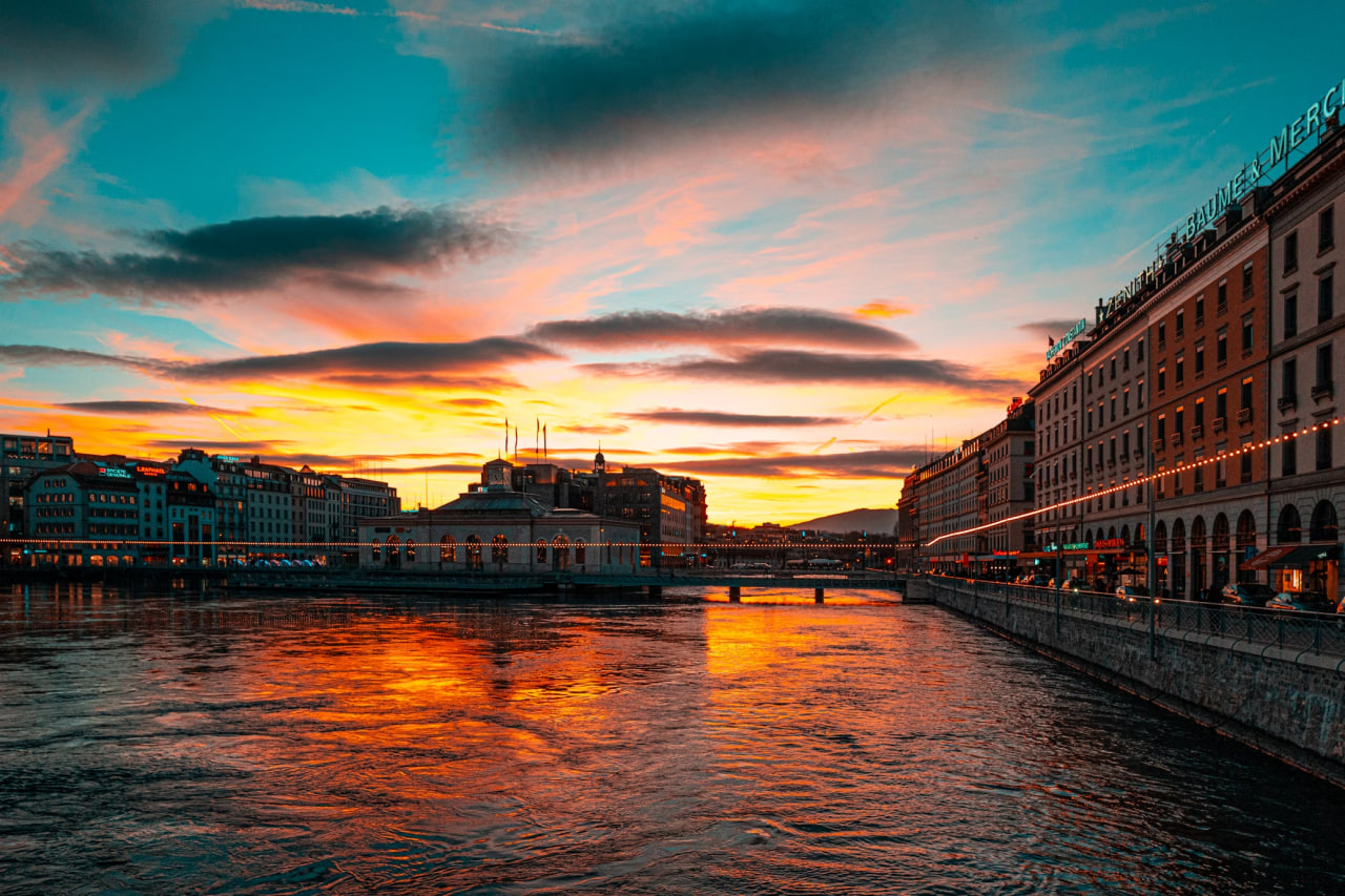 Sunset over the river in central Geneva with historic buildings and reflections on the water