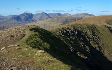Mountain ridge along Goat’s Water Round with distant fells under a clear blue sky