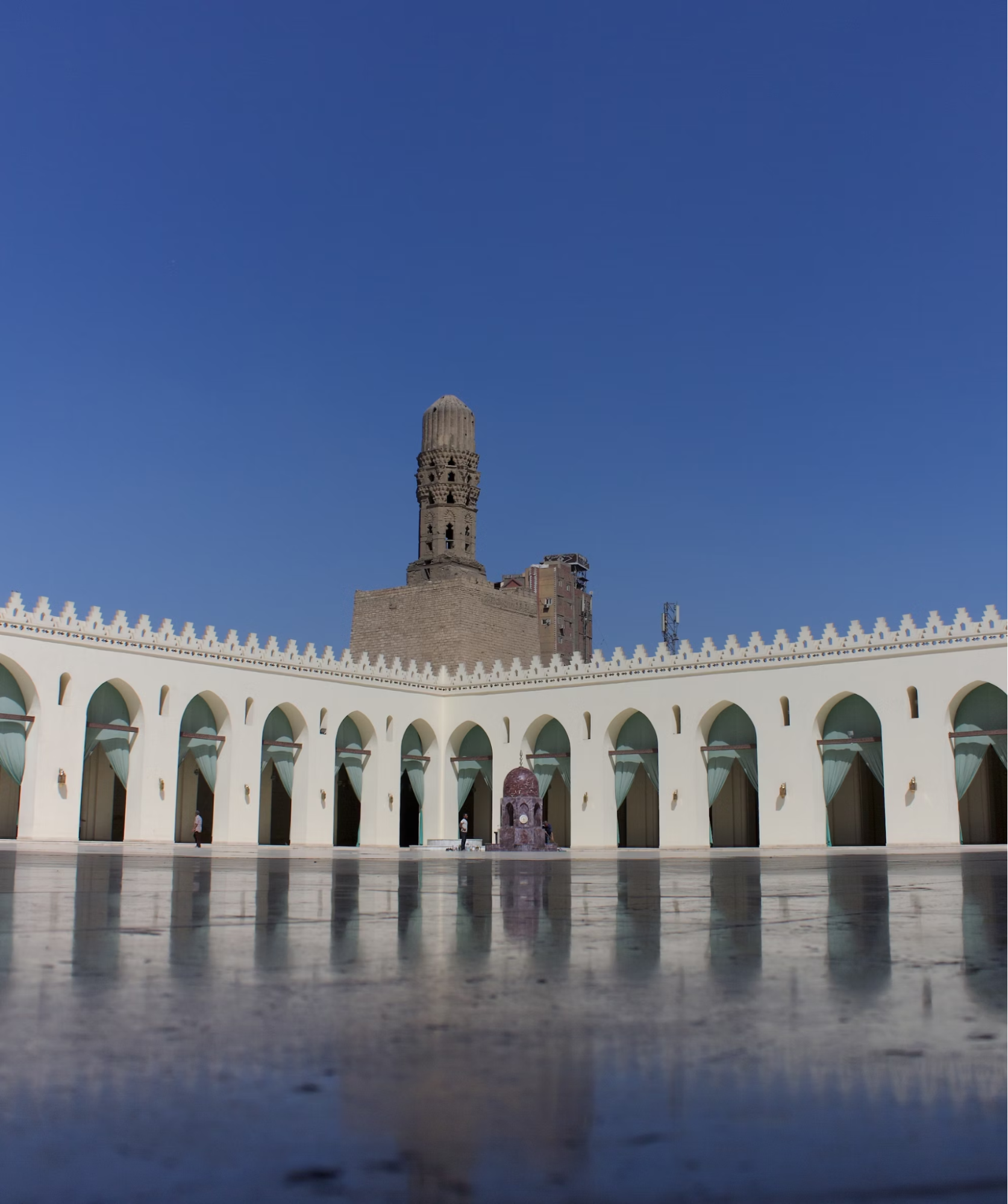 Courtyard of a historic mosque with minaret under clear blue sky