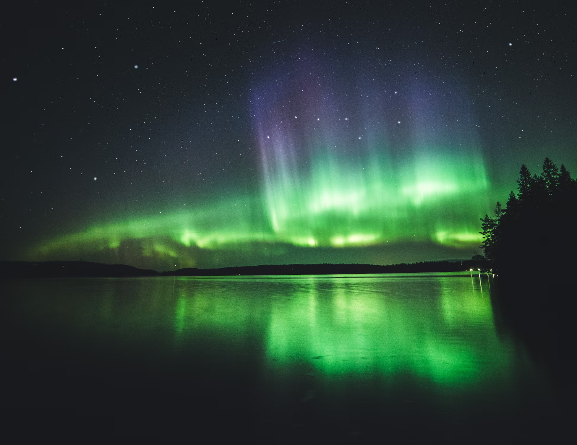 Northern lights glowing over a calm lake in Lapland at night