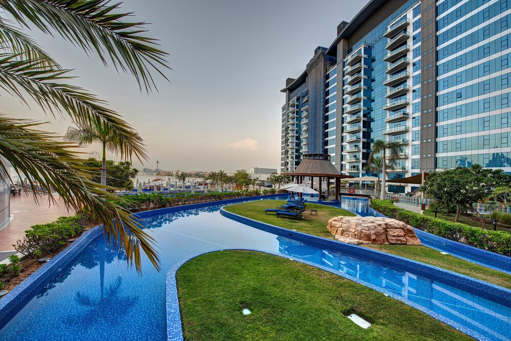 Modern hotel building with landscaped pool area on Dubai’s Palm West Beach