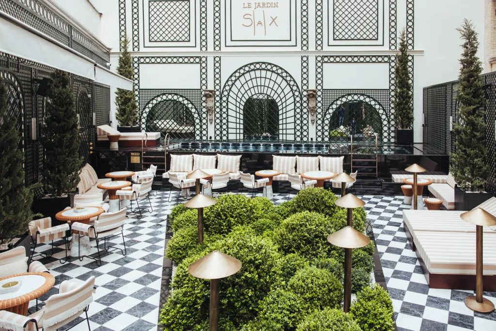 Stylish hotel courtyard with plunge pool, checkerboard floor, greenery, and striped lounge seating