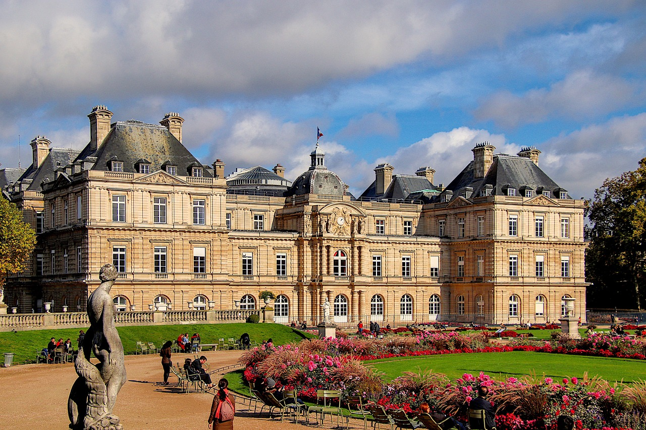 View of the Luxembourg Palace and gardens with blooming flowers and visitors in Jardin du Luxembourg