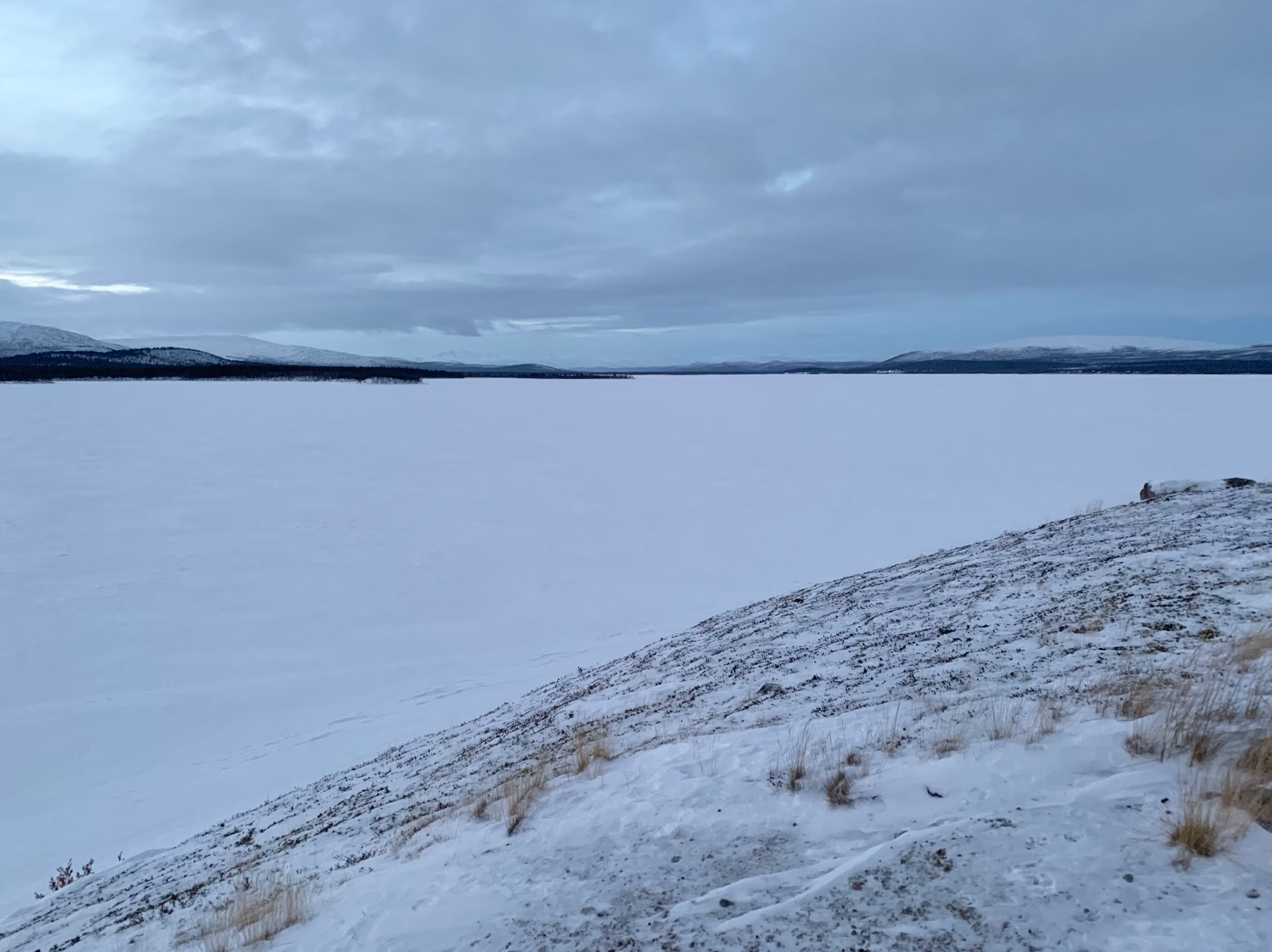Snow-covered Hietajärvi lake under a cloudy winter sky in Finnish Lapland