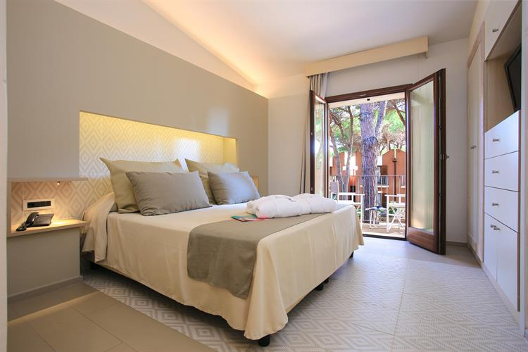 Modern hotel room with balcony view of pine trees in Sardinia