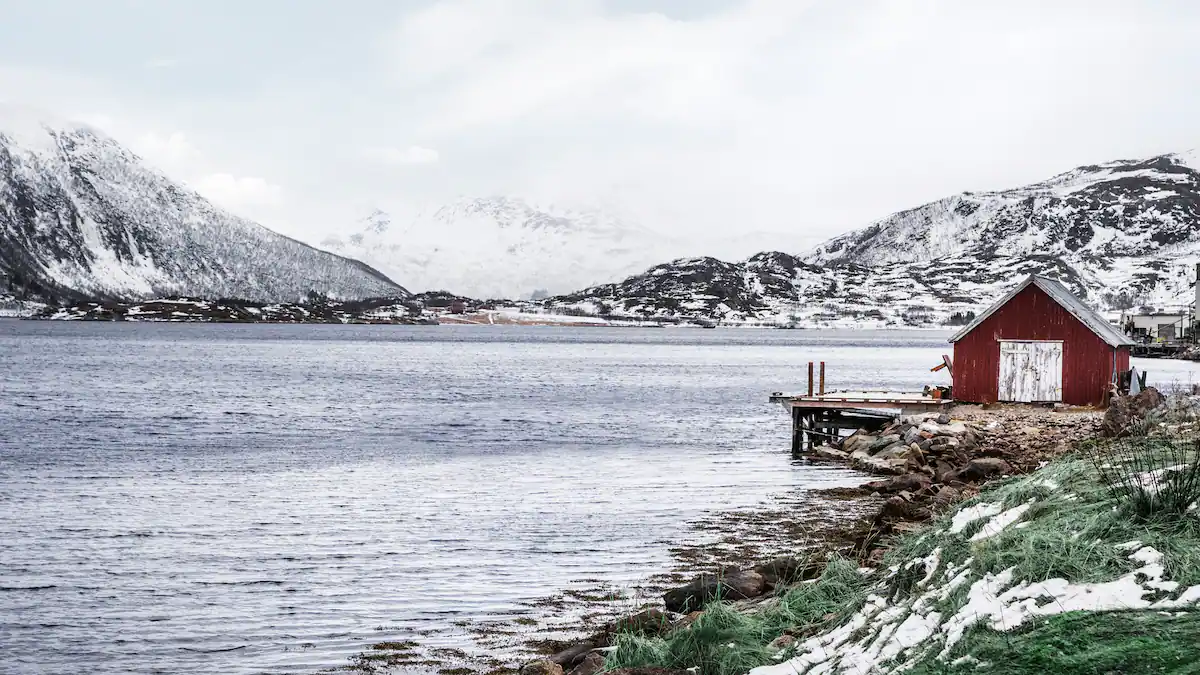 Red cabin by a fjord with snow-covered hills near Oslo