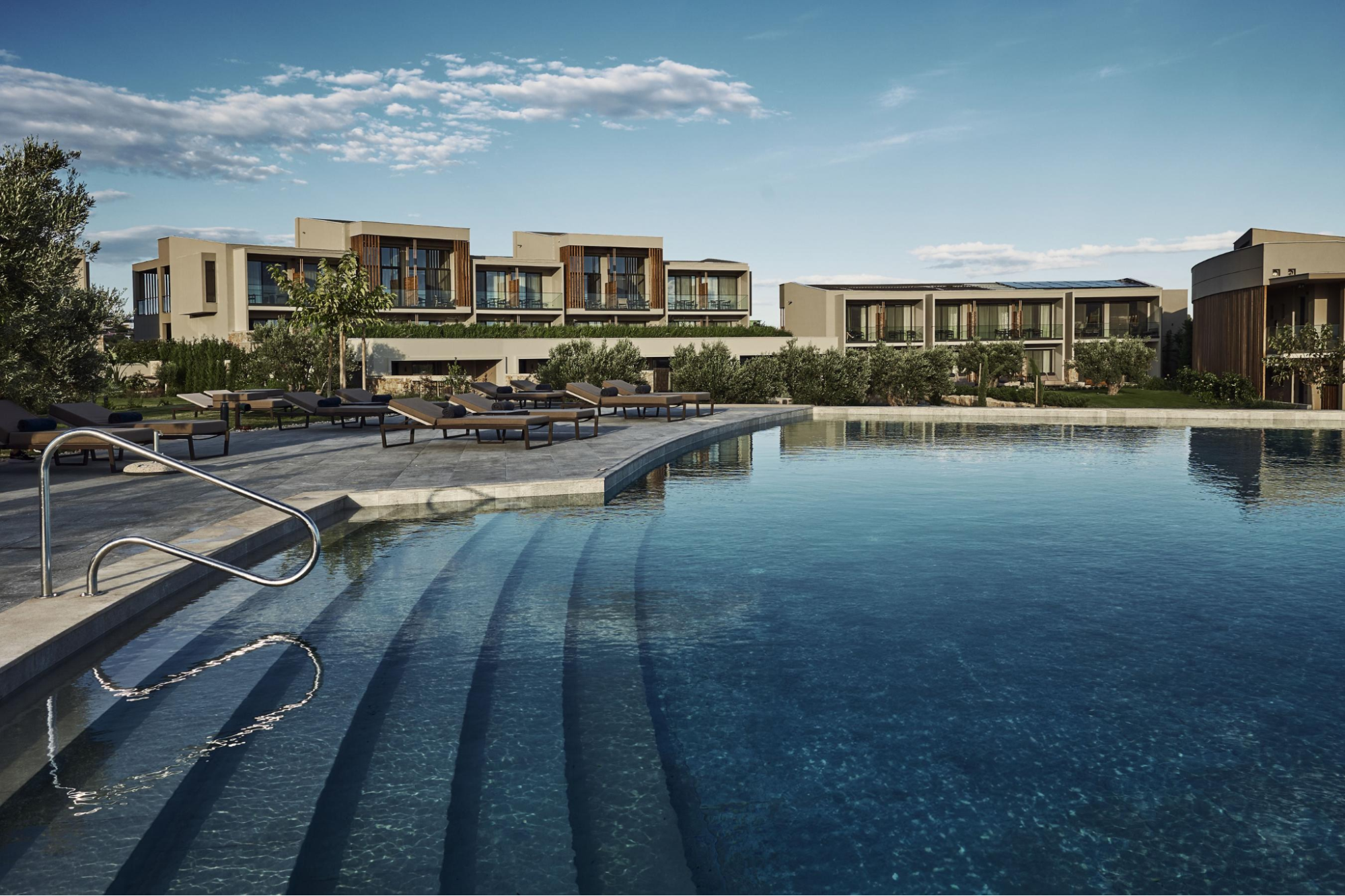 Outdoor pool area at Zélia Halkidiki adults-only resort with modern suites in the background