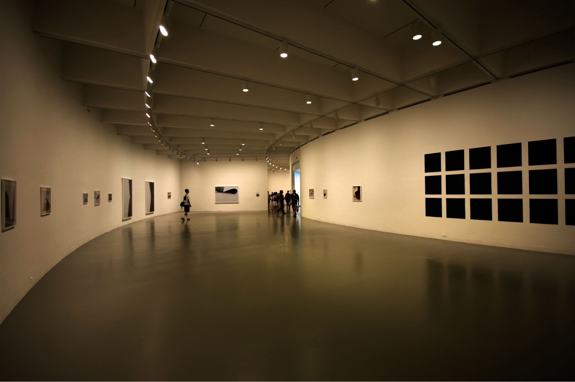 Modern art gallery with visitors walking inside curved exhibition hall