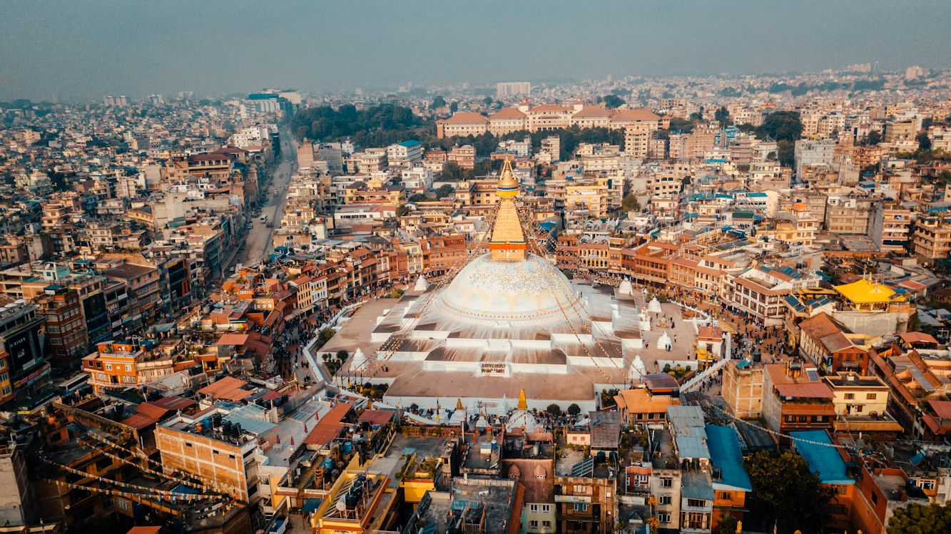 Aerial view of Boudhanath Stupa surrounded by dense urban buildings in Kathmandu